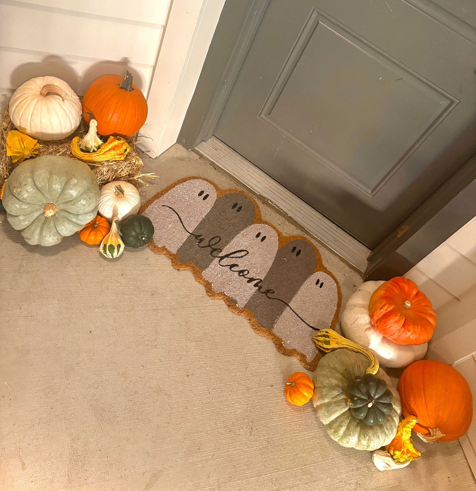 Heirloom and white pumpkins styled by hand around a front-door welcome mat