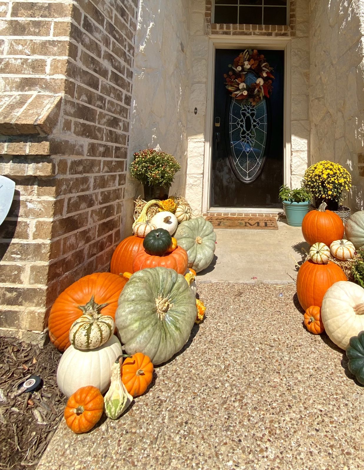 Front walkway lined with real pumpkins, gourds, and mums styled by Frontstep Harvest